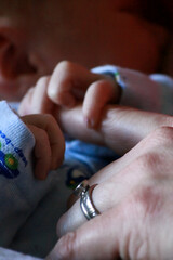 Tiny newborn's hand gently grasps mother's finger