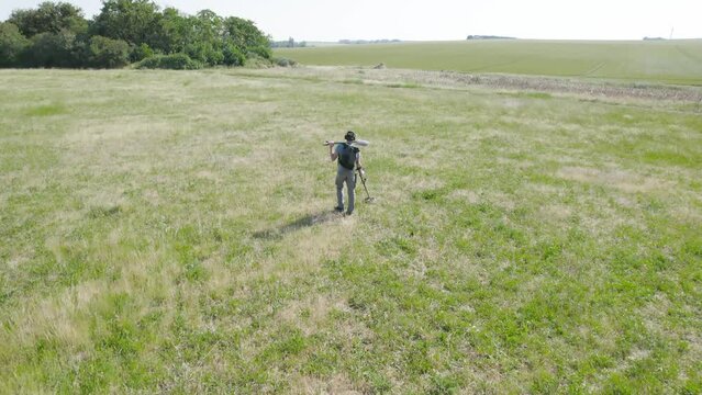 Aerial View Of A Man Metal Detecting In The Grassland.