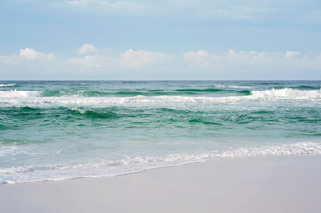 Waves crashing on a sandy beach under a clear sky