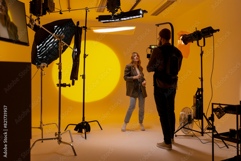 Wall mural Videographer capturing footage in a yellow room with a camera