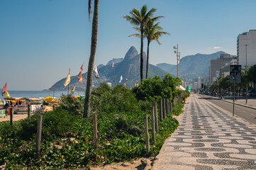 Obraz premium View of Leme beach and Copacabana beach with palms and mosaic of sidewalk in Rio de Janeiro, Brazil. Copacabana beach is the most famous beach in Rio de Janeiro. Sunny cityscape of Rio de Janeiro