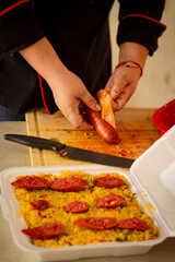 Latin woman prepares chorizo ​​for a paella in her small business