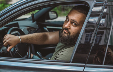 Obraz premium Portrait of bearded men in car, close up. Guy with automobile. Concept of hobby, cars