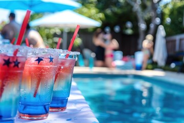 Festive beverages served at a pool party, featuring red, white, and blue layered drinks adorned with star-shaped decorations and straws. The drinks are set against a backdrop of a sparkling pool.