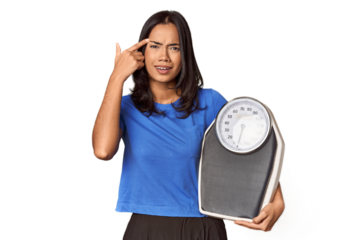 Filipino woman with scale in studio showing a disappointment gesture with forefinger.