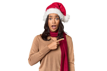 Filipino in Christmas attire and Santa hat pointing to the side