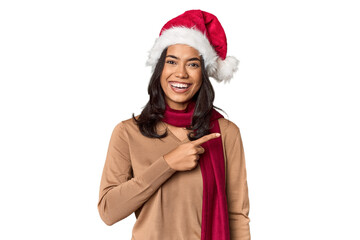 Filipino in Christmas attire and Santa hat smiling and pointing aside, showing something at blank space.