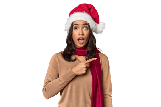 Filipino in Christmas attire and Santa hat pointing to the side