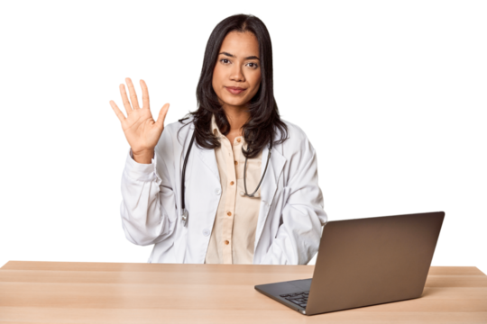 Young Filipino doctor with laptop in studio smiling cheerful showing number five with fingers.