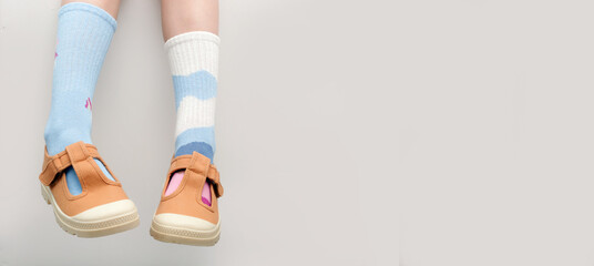 Kid wears different pair of socks. Child foots in mismatched socks, studio photography with copy...