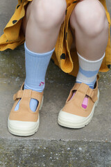 Kid wears different pair of socks. Child foots in mismatched socks, studio photography. Down syndrome awareness concept, odd socks day, anti-bullying week.