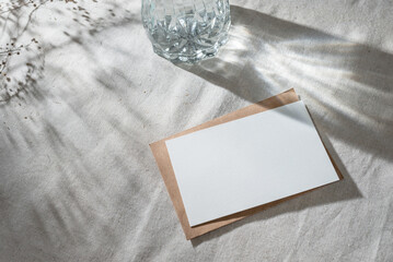 blank paper card mockup, envelope on neutral gray beige linen table cloth background with abstract...