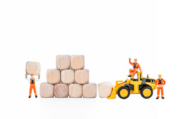 Miniature worker with wooden cube stack and yellow truck isolate on white background, business goal, building block to success