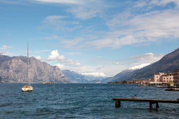 A sailing yacht floating near the pier against the background of mountains and a picturesque sea bay