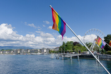 A six-band rainbow flag representing the LGBT community flutters in the wind on the Mont Blanc bridge and Lake Geneva