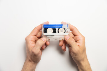 White and blue cassette in male hands on a white background, top view. Mock-up for an inscription on a magnetic cassette, an object of old luxury