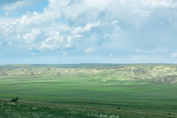 Green field in countryside at sunny day. Beautiful landscape in the mountains. Grassy field and hills. Travel Georgia