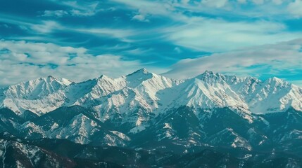 Fototapeta premium The mountains are cloaked in snow beneath a blue sky with distant wispy clouds