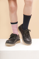 Kid wears different pair of socks. Child foots in mismatched socks, studio photography. Down...