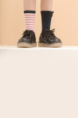 Kid wears different pair of socks. Child foots in mismatched socks, studio photography with copy...
