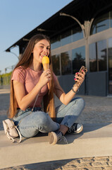 Woman sitting on the street eating an ice cream, looking at the camera. Vertical image