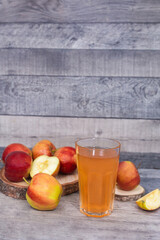Glass of apple juice and apple slice on wooden table. 