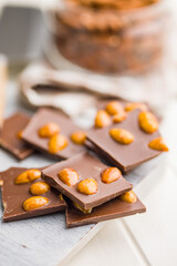 Broken chocolate bar with almonds on kitchen table.