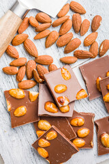 Broken chocolate bar with almonds on kitchen table.