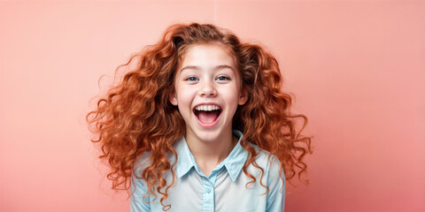Cute young child Little girl smiles. Emotion and child development. Little girl smiles while red hair. A young girl with curly hair is smiling and laughing while wearing a shirt.