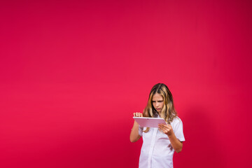 Online school app. Schoolgirl showing tablet computer Empty Screen Over red Background. Studio Shot