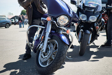 Two sleek motorcycles parked side by side in a vibrant parking lot, reflecting the sunlight on...