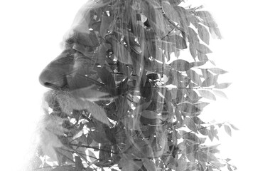 A double exposure profile of an old man blending into a photo of tree leaves