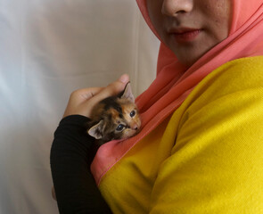 Young Asian Muslim Girl With Hijab Holding Cute Little Kitten With Care