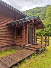 Horizontal photo of  wooden house in  green forest. Pros and cons of  wooden house and suburban real estate concept.