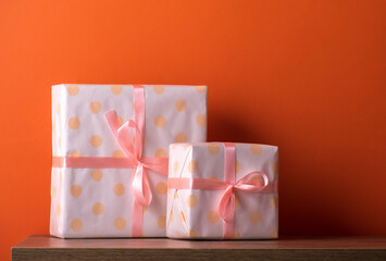 Cute present boxes on wooden table against orange wall.