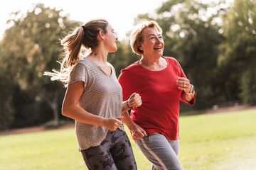 Happy grandmother and granddaughter jogging in park