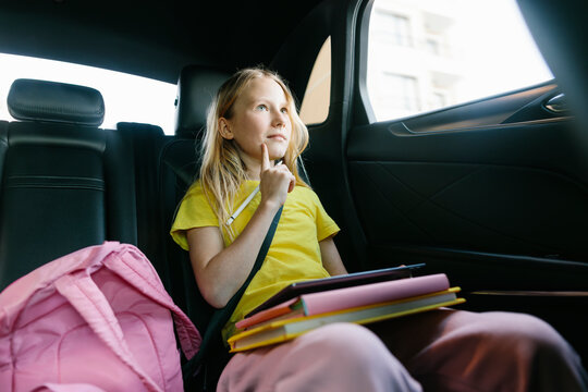 Thoughtful girl holding digitized pen and sitting in car