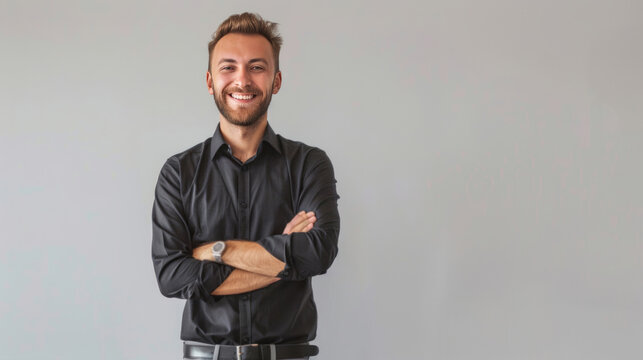 A handsome businessman in a black shirt and gray pants smiling and standing with his arms crossed, isolated on a white background.
