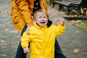 Little boy crying outside in a park. Candid portrait. Real emotions.