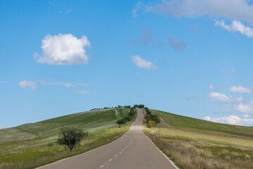 Road in green hills in sunny day. Georgia. Beautiful mountain roadway, green grass, blue sky, white clouds. Landscape