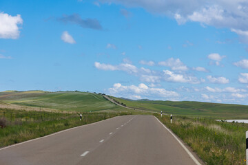 Road in green hills in sunny day. Georgia. Beautiful mountain roadway, green grass, blue sky, white clouds. Landscape