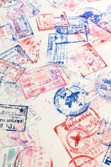 A white page features passport stamps from around the world, each stamp colored in different shades of pink and blue, symbolizing travel and adventure.