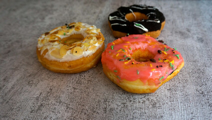 Sweet Food Donuts With Almond Topping, Chocolate And Pink Icing On Gray Background