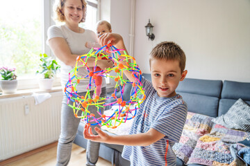 Boy holding expandable breathing ball with mother standing at home