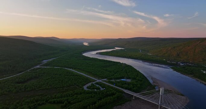 Aerial tracking shot of the Sami Bridge and the Tenojoki river, dusk in Utsjoki, Finland