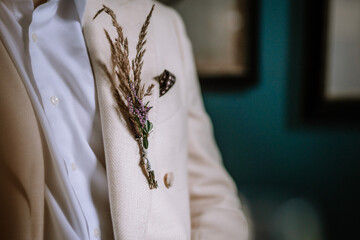 Riga, Latvia, - August 26, 2024 - A close-up of a beige suit with a boutonniere made of dried grasses and small flowers pinned to the lapel, showcasing elegance and style.