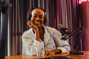 Radiant radio dj smiling in studio with professional microphone and headphones
