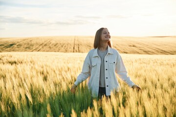 In white clothes, enjoying nature. Young woman is on the beautiful agricultural field at daytime