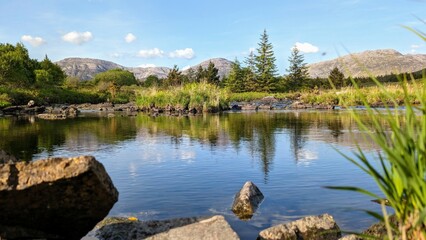 Beautiful landscape scenery, river with mountains and pine trees reflection, nature background Derryclare natural reserve at Connemara national park, county Galway, Ireland, wallpaper