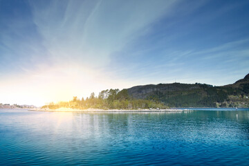 Obraz premium Island with rocks and trees in the fjord in front of the open sea in Norway.